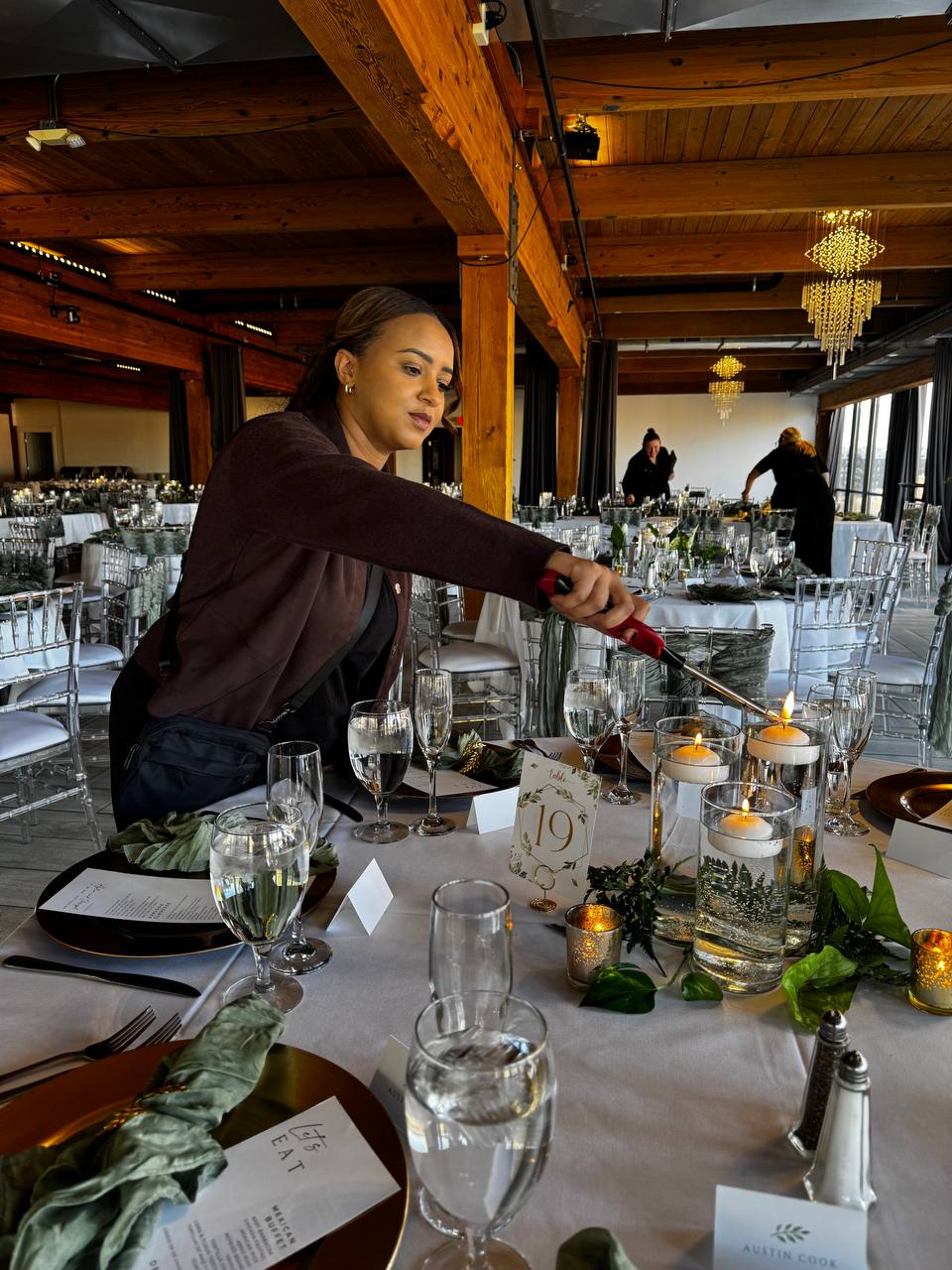 Harmony Events coordinator lighting candles on a finished reception table